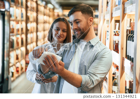 Glass with drink. Man and woman are choosing wine in the shop 131344921