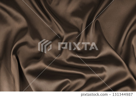 Crumpled, wrinkled brown colored glossy silk satin texture. Shiny smooth fabric with soft folds Crumpled, wrinkled brown colored glossy silk satin texture. Shiny smooth fabric with soft folds 131344987