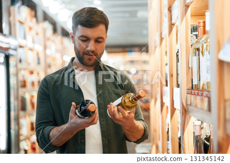 Front view. Man is choosing wine in the store Front view. Man is choosing wine in the store 131345142