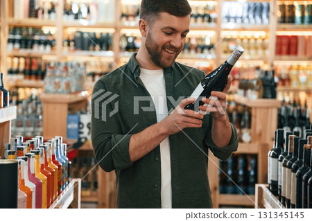 Front view. Man is choosing wine in the store 131345145