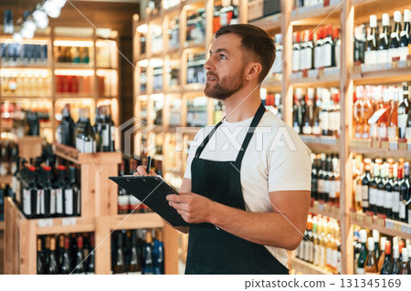 Quality control, with notepad. Wine shop owner in white shirt and black apron 131345169