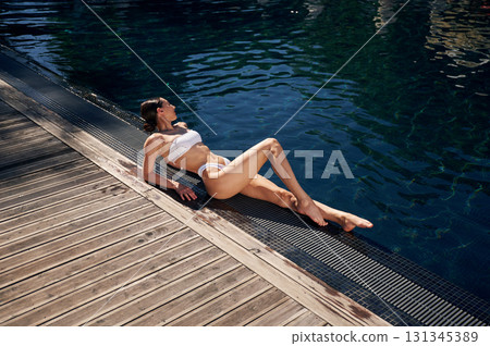 Near swimming pool. Woman in white bikini Near swimming pool. Woman in white bikini 131345389