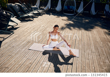 On the yoga mat. Young woman in fitness clothes is outdoors On the yoga mat. Young woman in fitness clothes is outdoors 131345415
