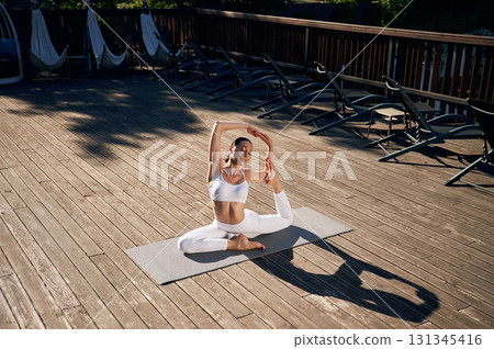 On the yoga mat. Young woman in fitness clothes is outdoors On the yoga mat. Young woman in fitness clothes is outdoors 131345416