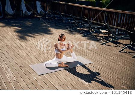 On the yoga mat. Young woman in fitness clothes is outdoors On the yoga mat. Young woman in fitness clothes is outdoors 131345418