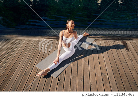 Makes twine. Young woman in fitness clothes is outdoors Makes twine. Young woman in fitness clothes is outdoors 131345462