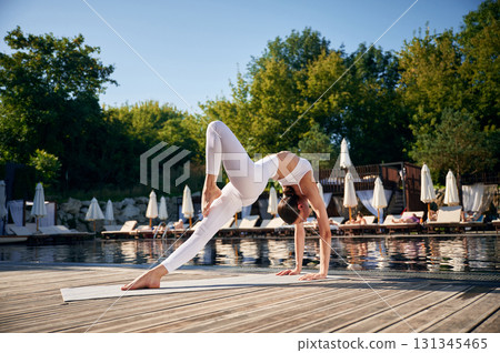 Spine exercises. Young woman in fitness clothes is outdoors 131345465