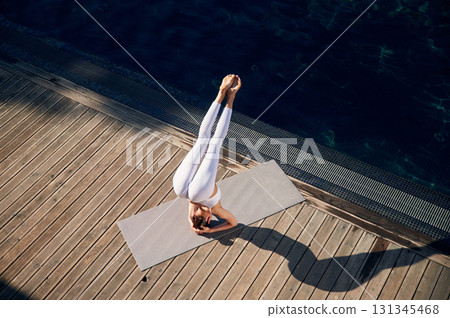 Spine exercises. Young woman in fitness clothes is outdoors 131345468