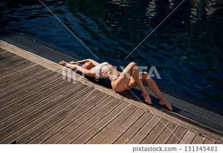 Top view, lying down. Woman in white bikini is near swimming pool Top view, lying down. Woman in white bikini is near swimming pool 131345481