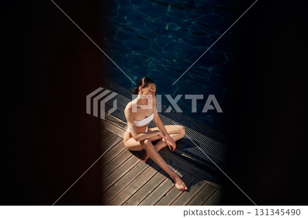 Resting, enjoying the vacation. Woman in white bikini is near swimming pool 131345490