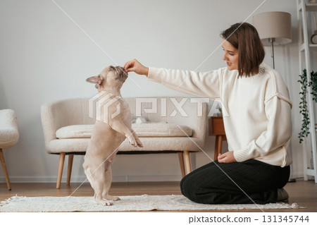 Playing together. Young woman is with her pug dog at home Playing together. Young woman is with her pug dog at home 131345744