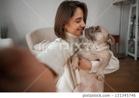 Making selfie, smiling. Young woman is with her pug dog at home Making selfie, smiling. Young woman is with her pug dog at home 131345746