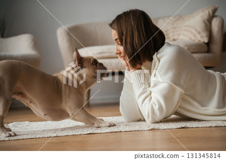 View from the side, lying down on the floor. Young woman is with her pug dog at home View from the side, lying down on the floor. Young woman is with her pug dog at home 131345814