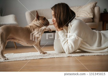 View from the side, lying down on the floor. Young woman is with her pug dog at home View from the side, lying down on the floor. Young woman is with her pug dog at home 131345815