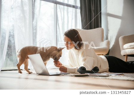 Using laptop. Young woman is with her pug dog at home 131345827