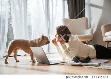 With laptop. On the floor. Young woman is with her pug dog at home 131345831