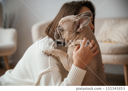 Holding pet in hands, care and love. Young woman is with her pug dog at home 131345853