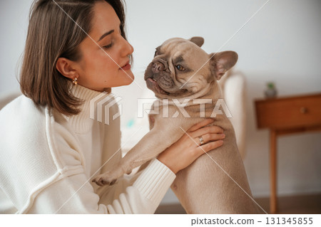 Holding pet in hands, care and love. Young woman is with her pug dog at home 131345855