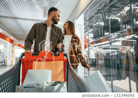 Buy me new clothes. Young couple are in supermarket together Buy me new clothes. Young couple are in supermarket together 131346093