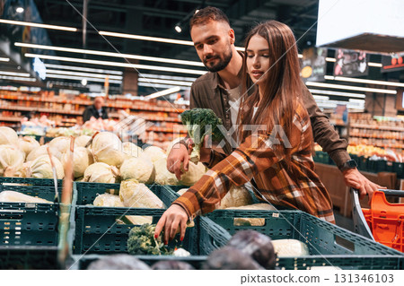 Fresh vegetables. Young couple are in supermarket together 131346103
