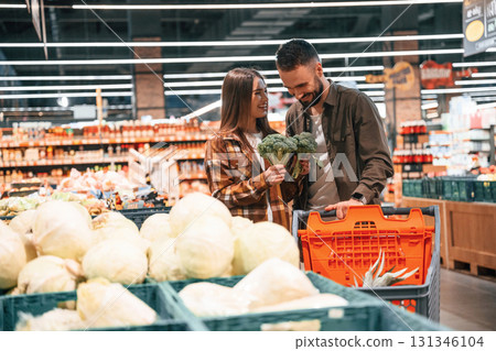 Fresh vegetables. Young couple are in supermarket together 131346104