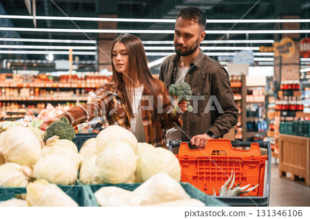 Fresh vegetables. Young couple are in supermarket together 131346106