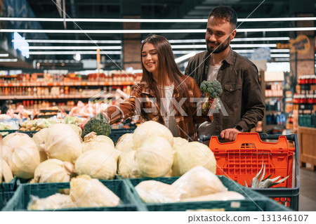 Fresh vegetables. Young couple are in supermarket together 131346107