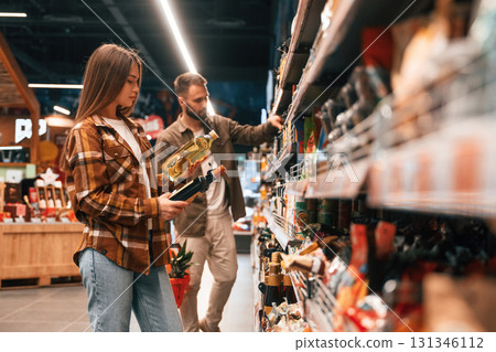 Oil in hands. Young couple are in supermarket together Oil in hands. Young couple are in supermarket together 131346112