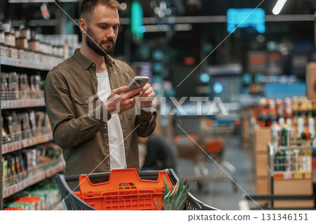 Checking information in the phone. Man is shopping in the supermarket 131346151