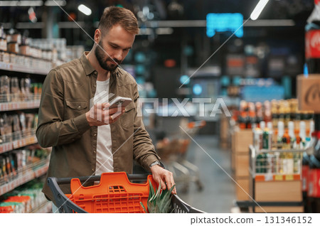 Checking information in the phone. Man is shopping in the supermarket Checking information in the phone. Man is shopping in the supermarket 131346152