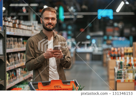 Checking information in the phone. Man is shopping in the supermarket Checking information in the phone. Man is shopping in the supermarket 131346153