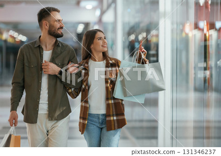 In casual clothes, with bags, shopping. Young couple are in supermarket together 131346237