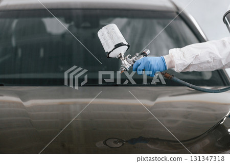 Close up view of man that is painting a car by using spray guy 131347318