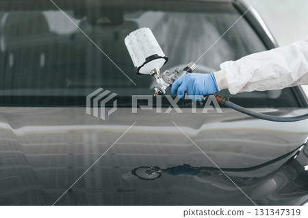Close up view of man that is painting a car by using spray guy 131347319