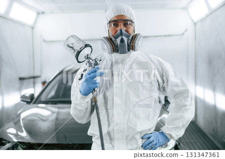 Customer service. Man is standing and holding spray gun with paint for automobile Customer service. Man is standing and holding spray gun with paint for automobile 131347361