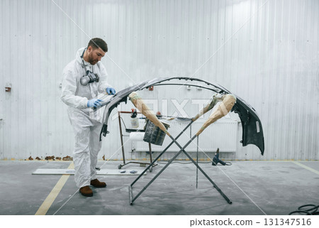 Unfinished part. Repairman is working with carcass of the car in the garage Unfinished part. Repairman is working with carcass of the car in the garage 131347516