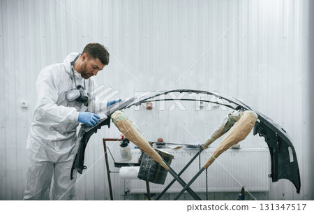 Unfinished part. Repairman is working with carcass of the car in the garage Unfinished part. Repairman is working with carcass of the car in the garage 131347517