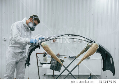 Side view. Repairman is working with carcass of the car in the garage Side view. Repairman is working with carcass of the car in the garage 131347519