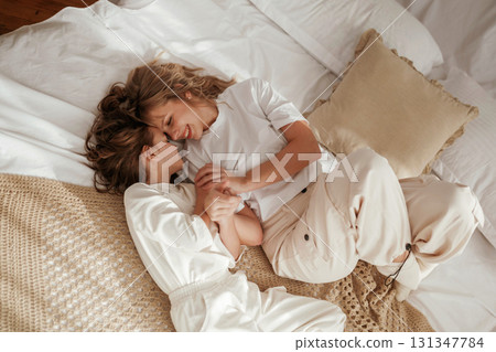 View from the top, lying down on bed. Mother with daughter are at home together View from the top, lying down on bed. Mother with daughter are at home together 131347784
