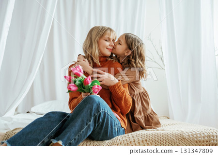 Flowers in hands. Mother's day concept. Female parent with daughter is at home Flowers in hands. Mother's day concept. Female parent with daughter is at home 131347809