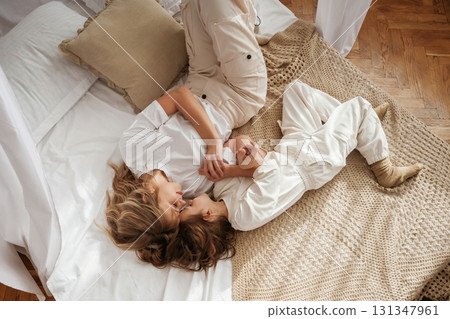 Top view, lying down on the bed. Mother with daughter are at home together 131347961