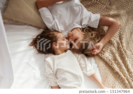 Top view, lying down on the bed. Mother with daughter are at home together Top view, lying down on the bed. Mother with daughter are at home together 131347964