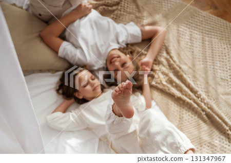 Top view, lying down on the bed. Mother with daughter are at home together Top view, lying down on the bed. Mother with daughter are at home together 131347967