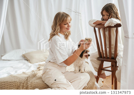 Dog pet is with them. Mother with daughter are at home together Dog pet is with them. Mother with daughter are at home together 131347973