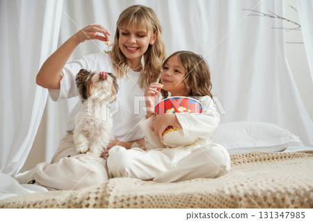 Watching movie with popcorn and dog. Mother with daughter are at home together Watching movie with popcorn and dog. Mother with daughter are at home together 131347985