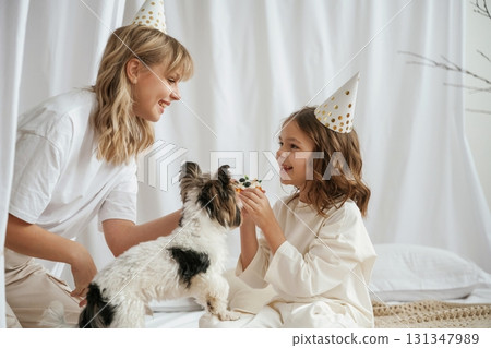 Celebrating birthday, in hats. Mother with daughter are at home together Celebrating birthday, in hats. Mother with daughter are at home together 131347989