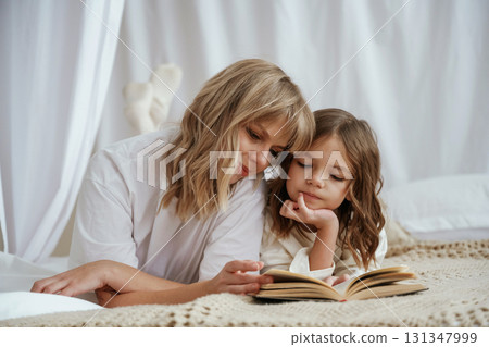 Reading the book together. Mother with daughter are at home Reading the book together. Mother with daughter are at home 131347999