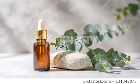 Amber Bottle with Golden Dropper, Eucalyptus Leaves and Stone Composition 131348073