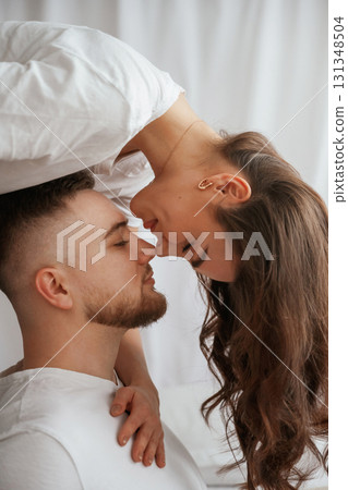 Woman is standing above man, willing to kiss. Young couple are together at home Woman is standing above man, willing to kiss. Young couple are together at home 131348504