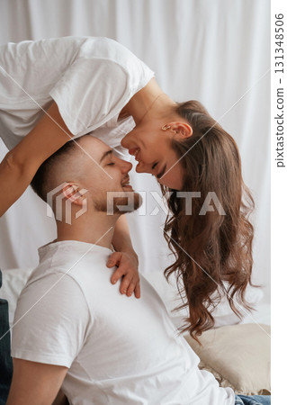 Woman is standing above man, willing to kiss. Young couple are together at home 131348506